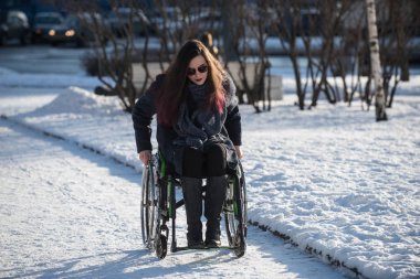 Saint-Petersburg, Rusya - 27 Şubat 2017: Bir şehir parkında tekerlekli sandalyede yürüyen güzel bir kız.