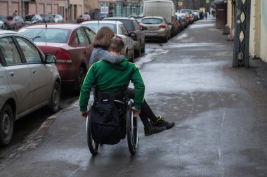 Saint-Petersburg, Rusya - 18 Şubat 2017: Tekerlekli sandalyedeki yakışıklı engelli genç adam ve sokakta bir kız