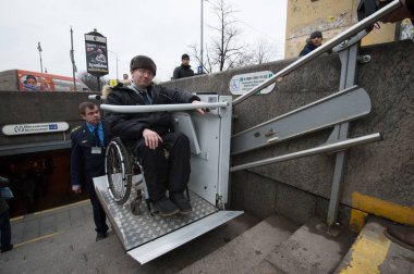 Saint-Petersburg, Rusya-2 Mart 2017: İşçi yeraltı yardımcı oluyor tekerlekli sandalyeli engelli kişi için merdivenlerde bir özel kaldırma aygıt ile hareket etmek için.