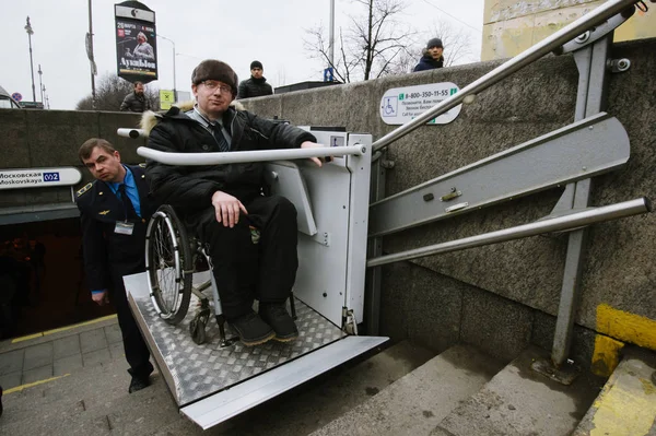 俄罗斯圣彼得堡 2017 地下工作者帮助向坐在轮椅上的伤残人士四处走动在楼梯上 与一种特殊的起重装置 — 图库照片