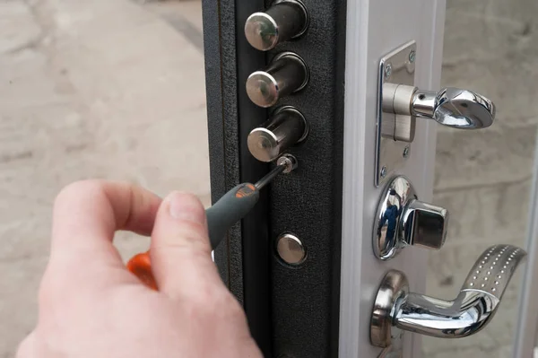 The carpenter installs a reliable burglar-resistant lock in the metal door.