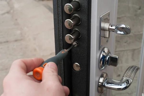 The carpenter installs a reliable burglar-resistant lock in the metal door.
