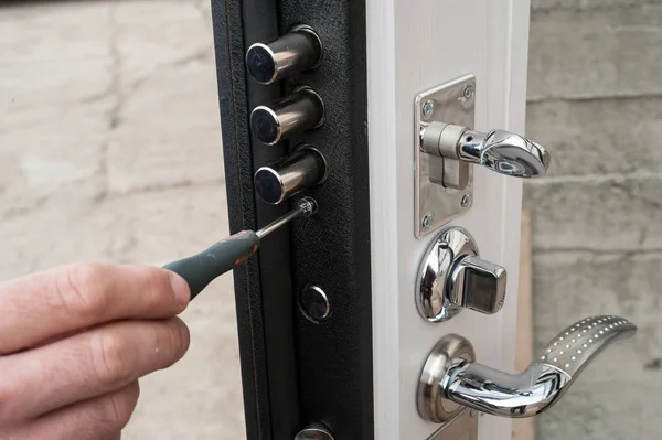 The carpenter installs a reliable burglar-resistant lock in the metal door.