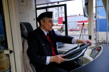 Direksiyonun başında bir melez troleybüs-otobüs sürücüsü