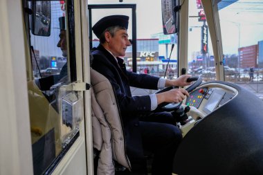 Direksiyonun başında bir melez troleybüs-otobüs sürücüsü