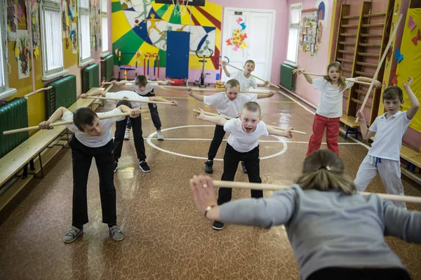 Leningrad Oblast, Rusya Federasyonu - 12 Mayıs 2017: bir beden eğitimi sınıfta çocuklar bir öğretmen rehberliğinde bir egzersiz - eğilir jimnastik sopa ile gerçekleştirmek.