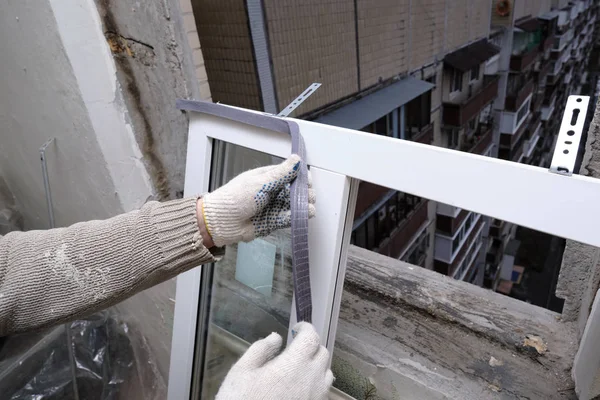 Fita isolante de ligação a uma janela de plástico durante a instalação . — Fotografia de Stock