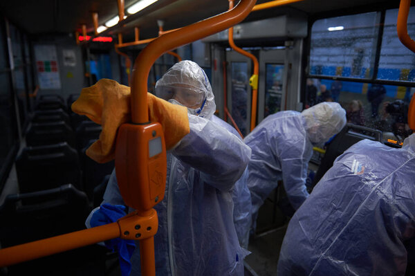 St. Petersburg, Russia - March 19, 2020: A team of orderlies in protective masks, caps and overalls perform sanitary cleaning of the tram's interior, coronavirus preventive measure