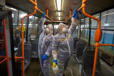 St. Petersburg, Rusya - 19 Mart 2020: COVID-19 salgınına karşı önleyici bir önlem olarak toplu taşımanın dezenfekte edilmesi. Tramvayın içiyle özel korumalı tulumlu çalışanlar ilgileniyor.