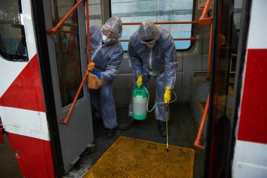 St. Petersburg, Rusya - 19 Mart 2020: COVID-19 salgınına karşı önleyici bir önlem olarak toplu taşımanın dezenfekte edilmesi. Tramvayın içiyle özel korumalı tulumlu çalışanlar ilgileniyor.