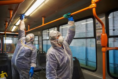 St. Petersburg, Rusya - 19 Mart 2020: COVID-19 salgınına karşı önleyici bir önlem olarak toplu taşımanın dezenfekte edilmesi. Tramvayın içiyle özel korumalı tulumlu çalışanlar ilgileniyor.