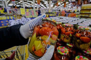 St. Petersburg, Rusya - 10 Nisan 2020: Salgın sırasında süpermarket. Alıcı elinde eldiven ve bir kavanoz tuzlanmış sebze tutuyor. Yakın plan.