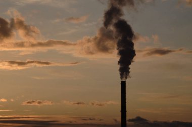 Gökyüzüne karşı çevresel kirliliğin sembolü olarak endüstriyel bir bacadan siyah duman. İllüzyon ve şehirdeki çevresel durum konsepti
