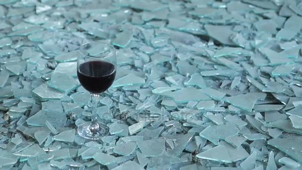 Een glas rode wijn op de scherven van glas — Stockvideo