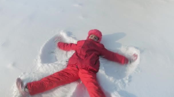 Flickan skildrar en ängel i snön. — Stockvideo