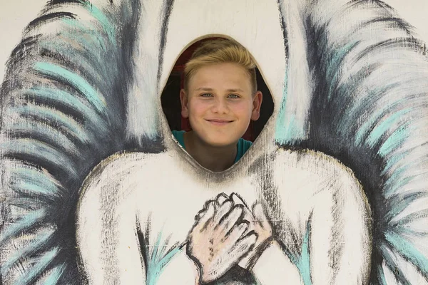 Smiling boy behind painting of angel — Stock Photo, Image