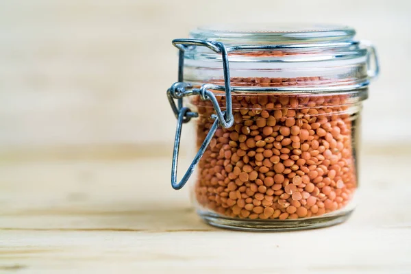 Glass Jar of Dried Red Lentils on Wood Table
