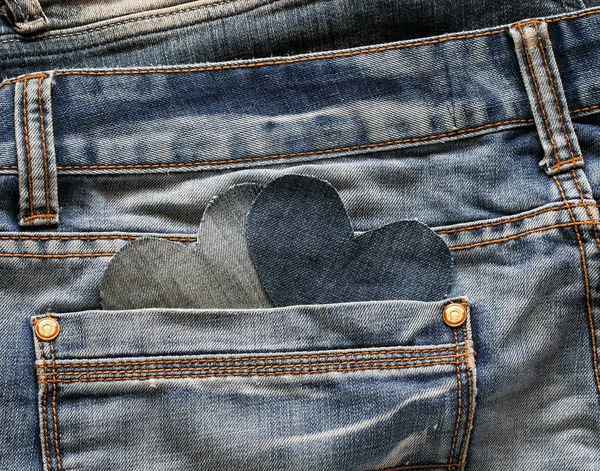 two stylish hearts are cut from blue denim peeks out from his po