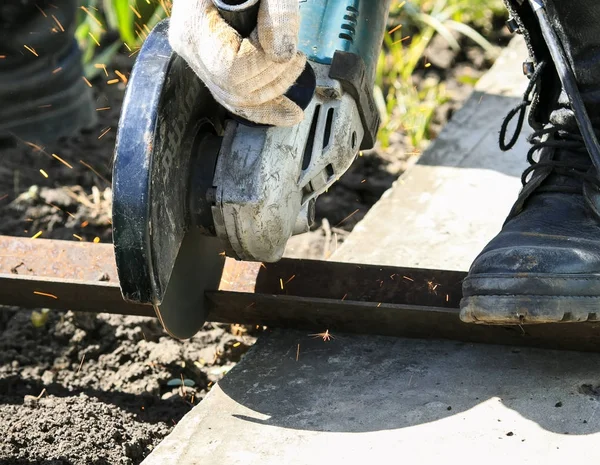 worker cuts a metal part using tool grinders and flying a bright