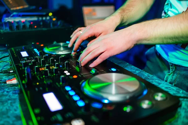 Mani di un DJ in un mixer per mixare musica in un'atmosfera da discoteca — Foto Stock