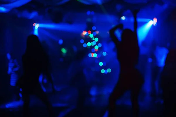 Chicas bailan en el club nocturno en el escenario unas siluetas borrosas — Foto de Stock