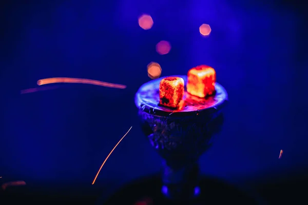 Shisha narguilé avec des braises rouges rougeoyantes et des étincelles volantes dans un bol sur fond bleu — Photo