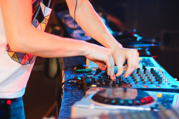 hands of DJ on mixer playing club music at party