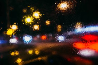 arabalar ve yağmur ile camın fener bulanık ışıkları ile gece şehir damla