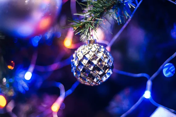 Кулькова іграшка на гілці ялинки на Новий рік з розмитим барвистим фоном світлої гірлянди на новий рік — стокове фото