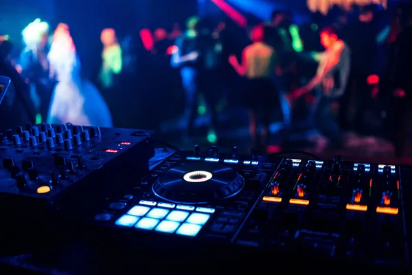 Ελέγχου Dj για μίξη μουσικής με θολή ανθρώπους να χορεύουν σε πάρτι στο νυχτερινό κέντρο διασκέδασης — Φωτογραφία Αρχείου
