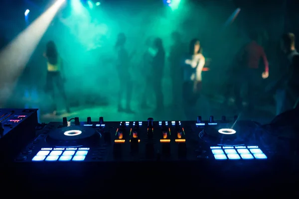 Музыкальный микшер в будке DJ в ночном клубе с людьми на танцполе и ночной атмосферой — стоковое фото