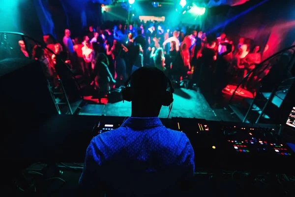 Silueta de DJ tocando música en el mezclador y un montón de gente bailando en discoteca en el escenario Imagen de archivo