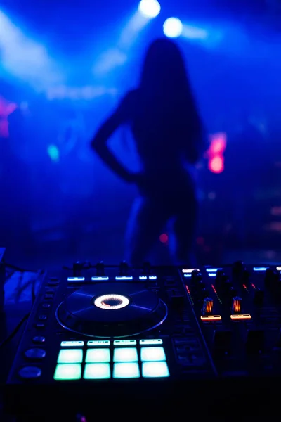 Silhouette of young slim dancers on stage out of focus through the DJ booth and a mixer — Stock Photo, Image