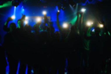 Fenerler gece kulübünde konserde ellerinde olan kişilerin bulanık siluetleri