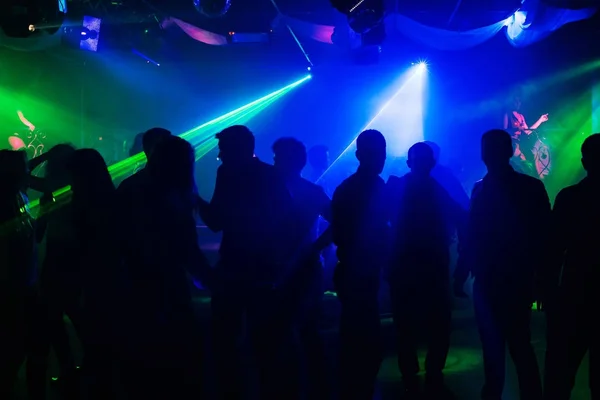 Sagome di persone su pista da ballo di club di notte a proiettori laser — Foto Stock