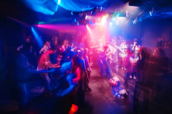Suddig silhuetter av människor i nattklubben på konsert med rörliga effekt på lång exponering — Stockfoto