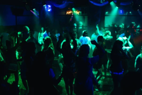 Verschwommene Silhouetten tanzen fröhliche Männer auf der Tanzfläche bei einem Konzert in einem Nachtclub — Stockfoto