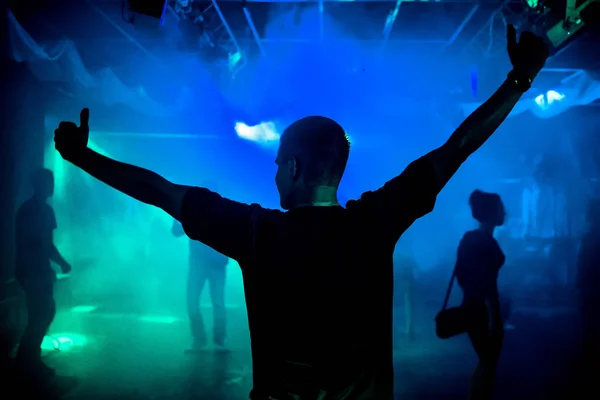 Silhouette of a young leading on dance floor of nightclub with a blue smoky background — Stock Photo, Image