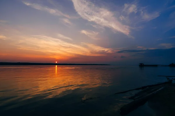 Puesta de sol sobre el río y el hermoso cielo en la noche de verano y silueta del muelle — Foto de Stock