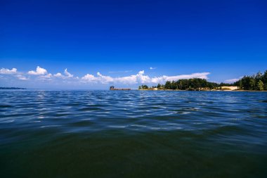 bir yaz gününde su üzerinde beyaz bulutlar ile mavi gökyüzü