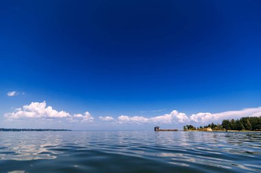 mavi açık gökyüzü yaz gününde su üzerinde beyaz bulutlar ile