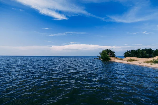 Γαλάζιο καθαρό ουρανό με τα κύματα στο νερό της θάλασσας και μια αμμώδη παραλία στη θερινή ημέρα — Φωτογραφία Αρχείου