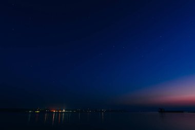 yıldızlı gece gökyüzü yıldız ve Nehri üzerinde parlayan şehir