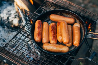 kamp on Fire rendeleyin üzerinde bir tavada kızarmış sosis