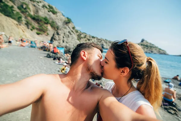 Paar von Reisenden macht Selfies und küsst sich am Strand auf Meeresgrund — Stockfoto