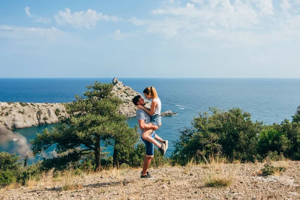 Çift yaz aylarında öğleden sonra dağlar deniz sarılma sevgi dolu. Adam kız ellerinde tutar.