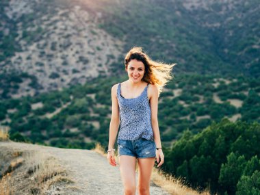 Güzel gülümseme ve uzun saç doğa üzerinde günbatımında poz ile mutlu kız