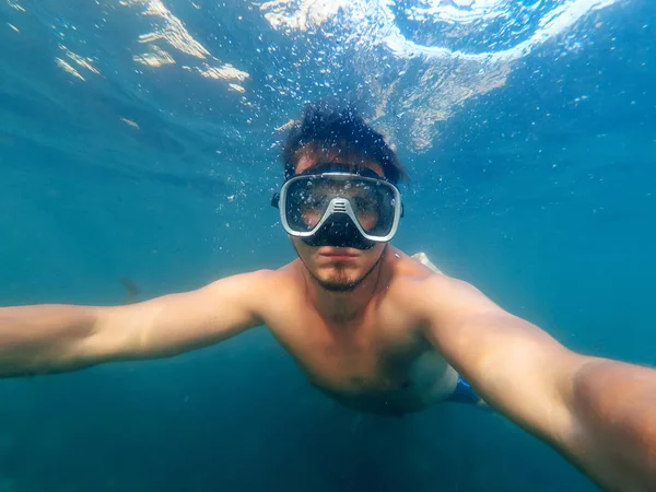 Mergulhador macho nada no mar sob a água azul com uma máscara — Fotografia de Stock