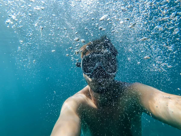 Manliga dykare simmar i havet under vatten med en mask och snorkel tar en selfie av ansiktet — Stockfoto