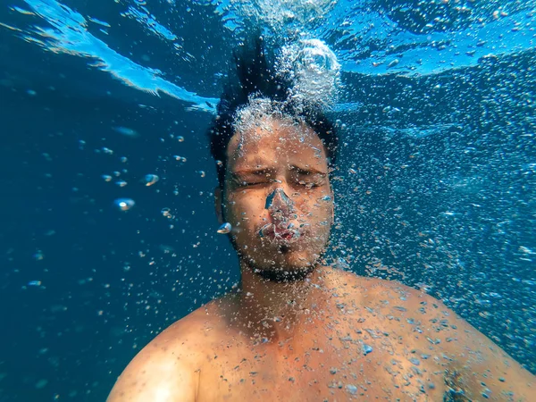 Muž pod vodou jímky na dno a vydání bubliny kyslíku — Stock fotografie
